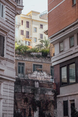 View to narrow old town street and ancient buildings on the side of this street with sky and other buildings in background.