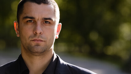 Close up portrait of serious caucasian millennial 30s elegant hispanic businessman boss director investor looking at camera posing male smart human face with stern eyesight standing in city outdoors