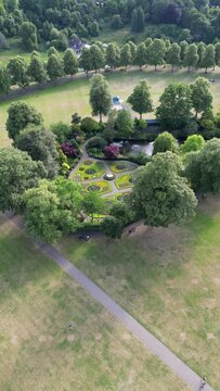Vertical drone footage of a beautiful garden with a small water pond in England
