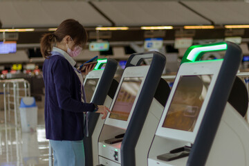 woman check in  her flight by electonic machine at airport