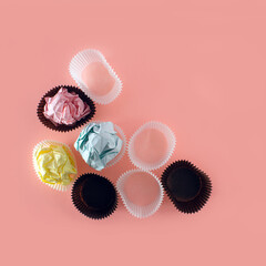 Cupcake liners and pastel paper balls, creative arrangement, party preparation idea, minimal layout on dusty rose pink background. 