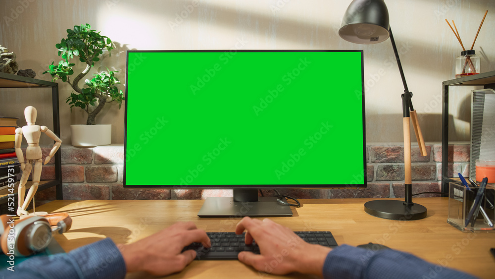 Fototapete POV First Person View of a Man Working on Desktop Computer with Green Screen Mock Up Display. Male Sitting at a Desk, Browsing Internet and Using Mouse at Home in Stylish Living Room.