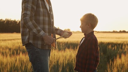 Farmer and his son in front of a sunset agricultural landscape. Man and a boy in a countryside field. Fatherhood, country life, farming and country lifestyle.