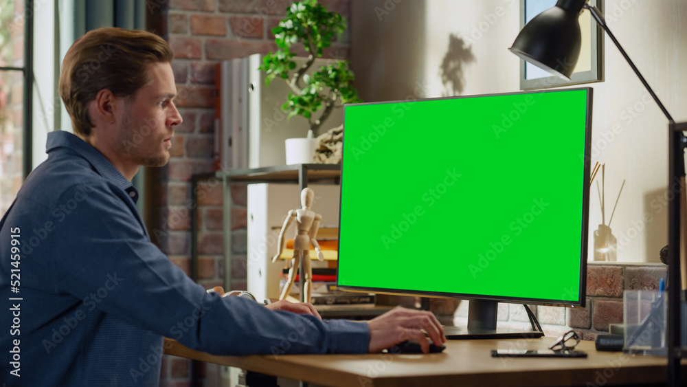 Aufkleber Young Handsome Man Working from Home on Desktop Computer with Green Screen Mock Up Display. Male Checking Corporate Accounts, Messaging Colleagues. Loft Living Room with Big Window.