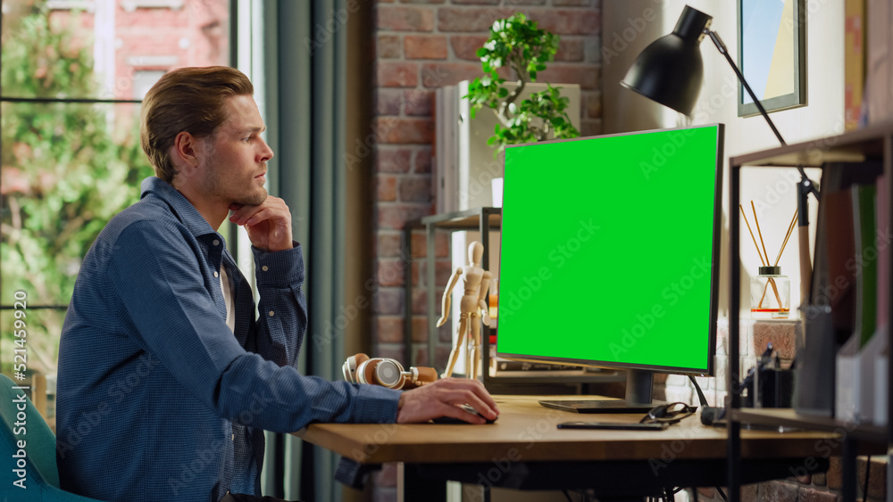 Aufkleber young handsome man working from home on desktop computer with green screen mock up display. male che