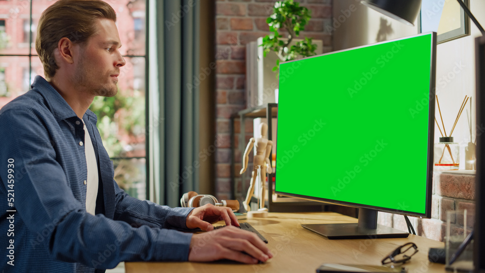 Aufkleber young handsome man working from home on desktop computer with green screen mock up display. male che