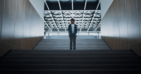 Sad boy standing alone on school staircase. Lonely guy posing at empty stairway