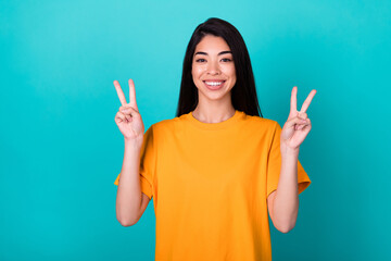 Photo of lovely young lady show v-sign wear orange t-shirt isolated on teal color background