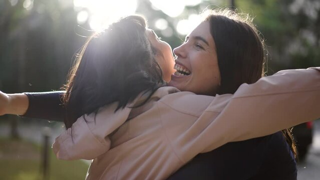 Two happy female best friends hugging each other. Women embrace reunion outdoors at park