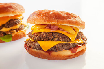Brioche donut double decker beef cheese burger with queso sauce with another burger in the background.
