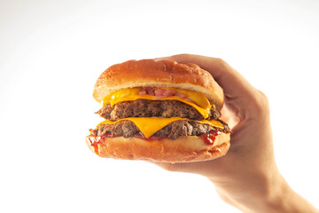 Hand holding a gourmet brioche cheese burger with queso sauce isolated on a white background