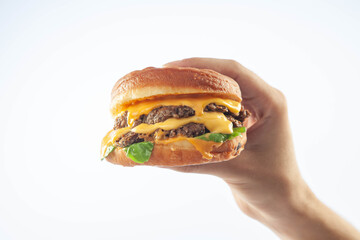 Hand holding a gourmet brioche cheese burger isolated on a white background