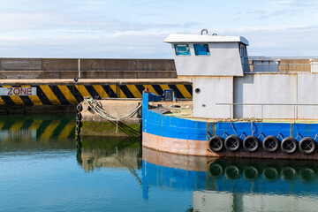 Fototapeta na wymiar 21 July 2022. Macduff, Aberdeenshire, Scotland. This is a Fish Farm Boat berthed at Macduff Harbour on a calm reflective afternoon.
