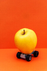Yellow apple on wheels. Delivery concept. Copy space. Isolated