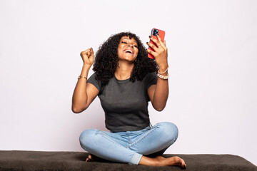 cheerful beautiful young black lady using her phone rejoices