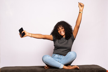 pretty black lady holding her phone feeling happy