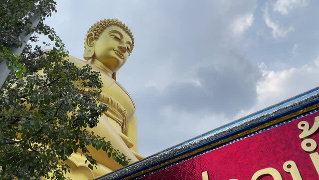Giant golden buddha statue at Wat Paknam Phasi Charoen, famous buddhist temple with blue sky background - day. BANGKOK, THAILAND 