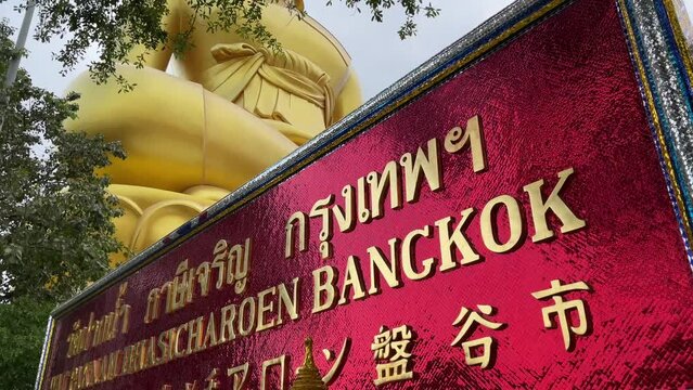 Wat Paknam Phasi Charoen golden sign. Famous giant buddha statue in background - day