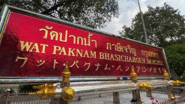 Wat Paknam Phasi Charoen golden sign. Trees in background - day
