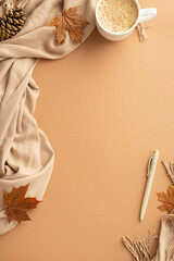 Autumn business concept. Top view vertical photo of workplace cup of frothy hot drinking fallen maple leaves pine cone pen and scarf on isolated beige background