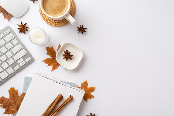 Obraz na płótnie Canvas Autumn business concept. Top view photo of keyboard computer mouse notepad candle cup of coffee rattan serving mat cinnamon sticks yellow maple leaves and anise on isolated white background