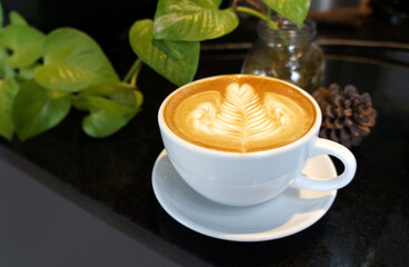 Hot coffee latte and heart shaped latte art in a white glass on a white background