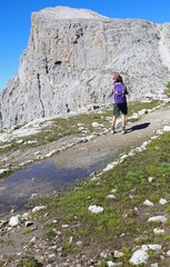 woman walking and the reflection of the mountain on the puddle of water