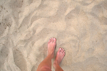 Female bare feet standing on beach sand