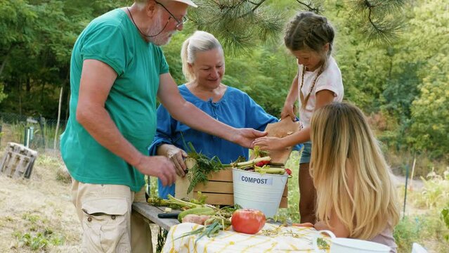 Grandfather and granddaughter high-five after putting vegetable scraps in a bin ready for  composting 