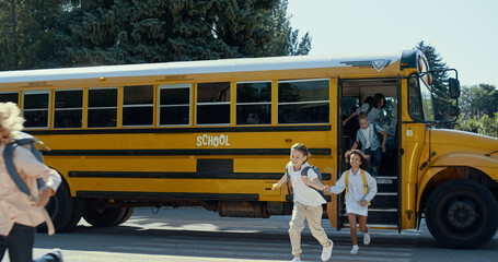 Smiling students leaving yellow school bus. Joyful pupils running on lessons.