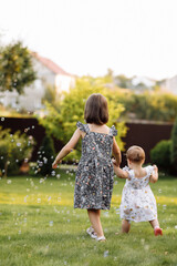 Fototapeta premium Two happy girls, adorable sisters are smiling happily together. Child girl holding hand her younger baby sister and playing outdoors on summer day holiday vacation, best friends.Family day