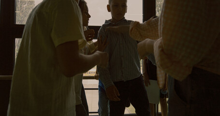 School bullies pushing helpless classmate together standing in circle hallway.