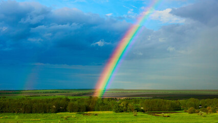 Naklejka premium The Rainbow over a field after thunderstorm