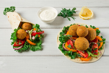 Tortillas, wrapped falafel balls, with fresh vegetables, vegetarian healthy food, on a wooden white...