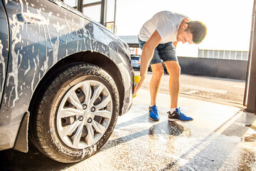 A man washes his car with foam at a self-service car wash