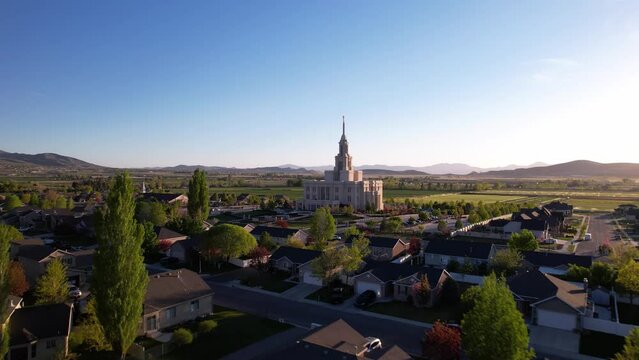 Aerial footage of Payson Utah Temple in the middle of trees and houses under the blue sky