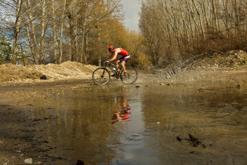 Cyclist crosses a stream with his bike and churns up the water.