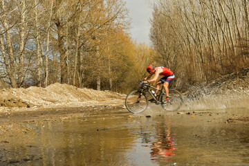 Cyclist crosses a stream with his bike and churns up the water.