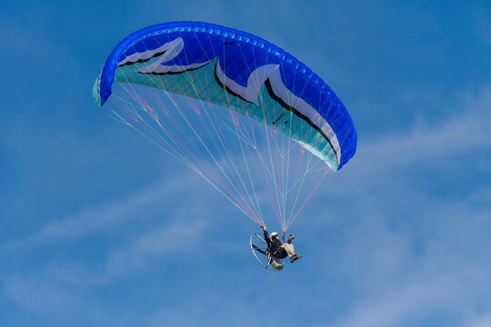 Flying with paramotor in the air on blue sky background.