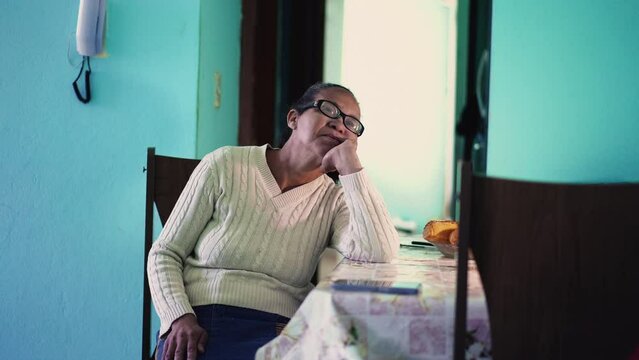 A thoughtful senior black woman sitting at home thinking by herself