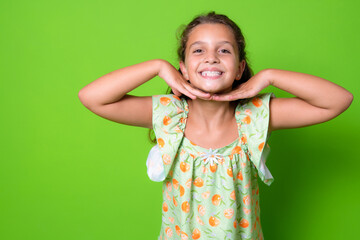 Close up portrait of cute happy smiling kid girl standing isolated over green background.