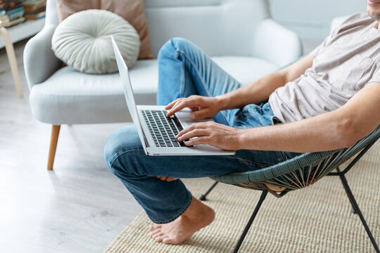 cropped image of a man using a laptop while sitting in a chair.