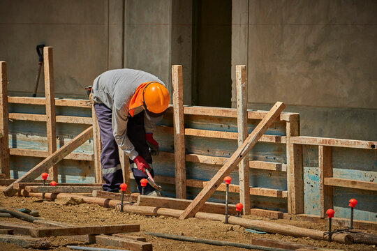 Trabajador de obra, martillando madera con todos sus implementos de seguridad 