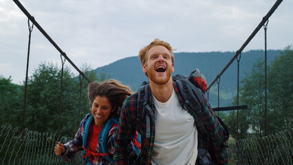 Travelers running nature mountains on river bridge. Happy couple holding hands.