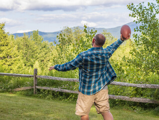man throwing football with mountains in background