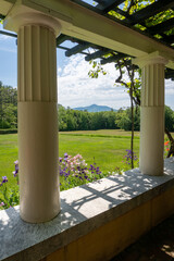 View of Mount Ascutney and  Connecticut River Valley. Purple iris, and Columbine flowers in the foreground. View from Little Studio at Saint-Gaudens National Historic Site. Colonnade and arbor.