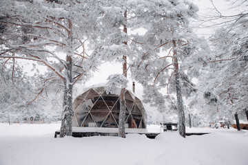 Glamping area with barbecue, dome tent and utility room in the snowy winter outdoors