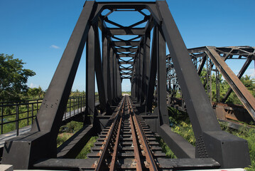 Railway is on black steel bridge.Perspective of steel bridge.