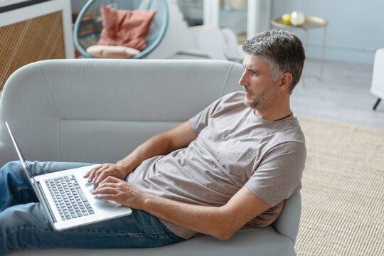 man with a laptop is resting in his living room.