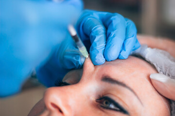 Kharkiv, Kharkiv Oblast, Ukraine - 08 18 2021: Botox injection into mimic wrinkles by a cosmetologist in a cosmetology office. Education